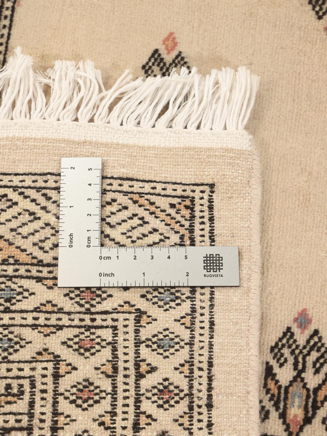 Een handgeknoopt Pakistan Bokhara tapijt met een beige veld en traditionele motieven.