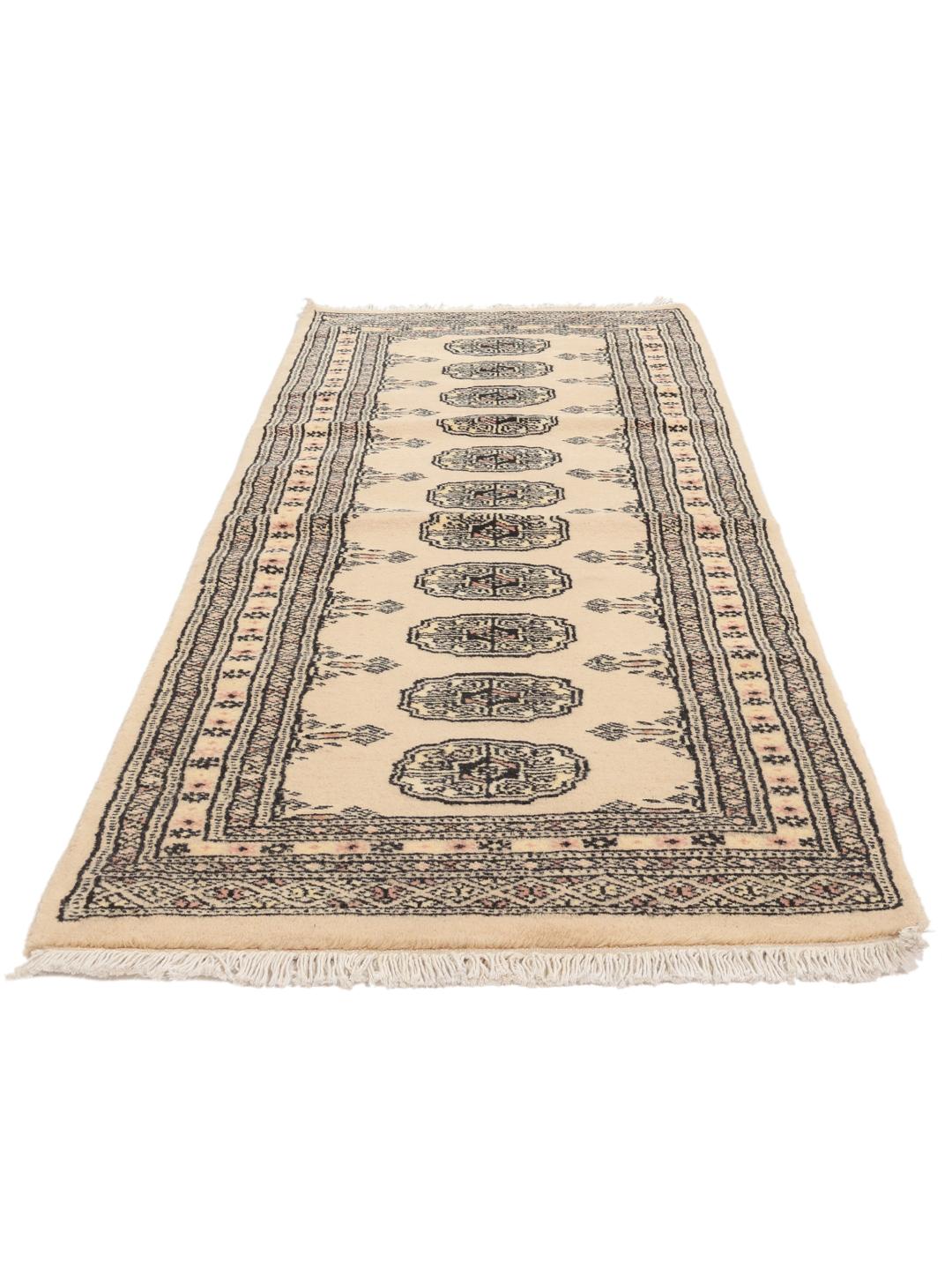 A hand-knotted Pakistan Bokhara runner rug in a soft beige colour with traditional geometric motifs.