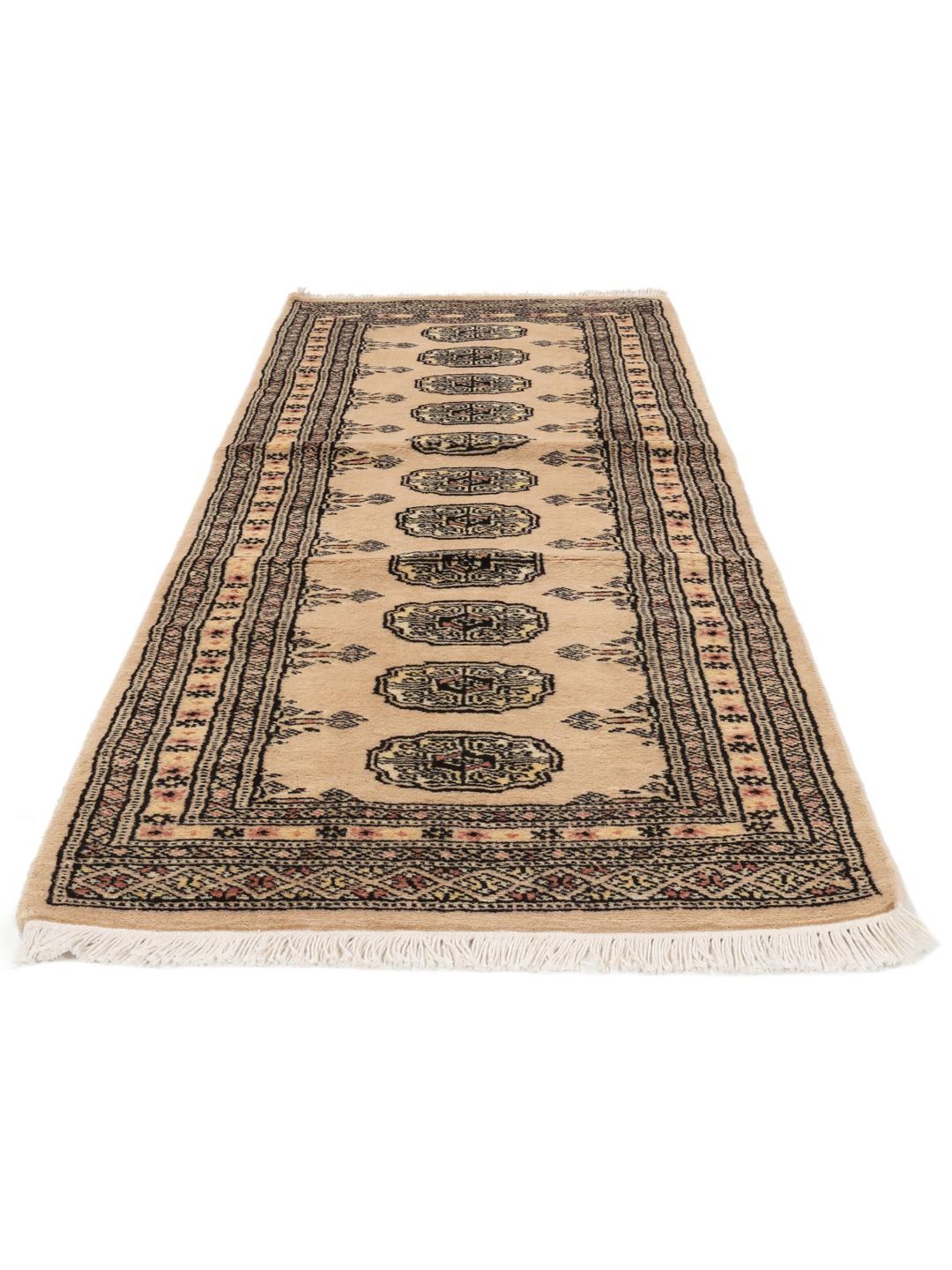 A hand-knotted Pakistan Bokhara runner rug in a soft beige colour with traditional geometric motifs.