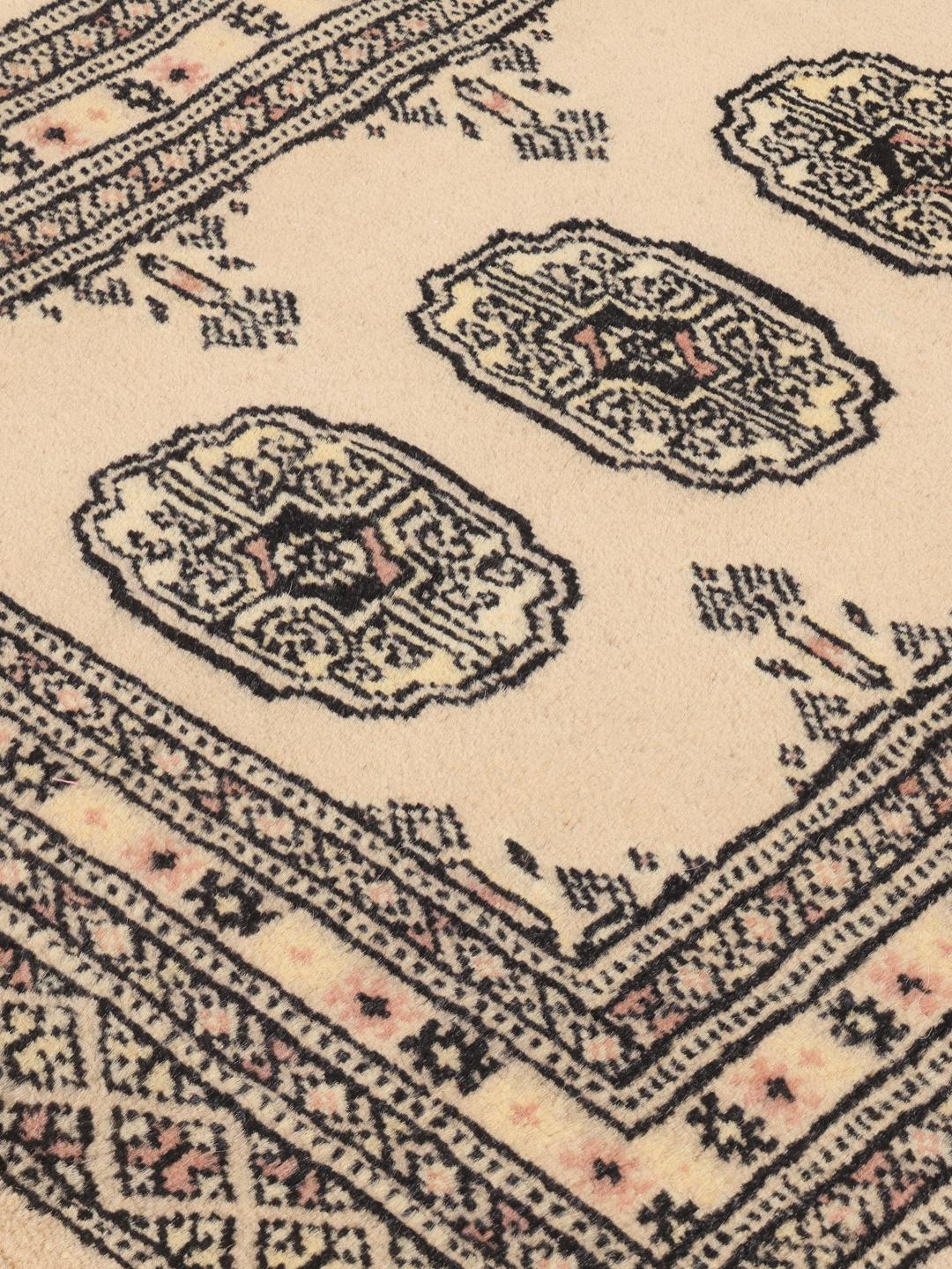 A hand-knotted Pakistan Bokhara runner rug in a soft beige colour with traditional geometric motifs.