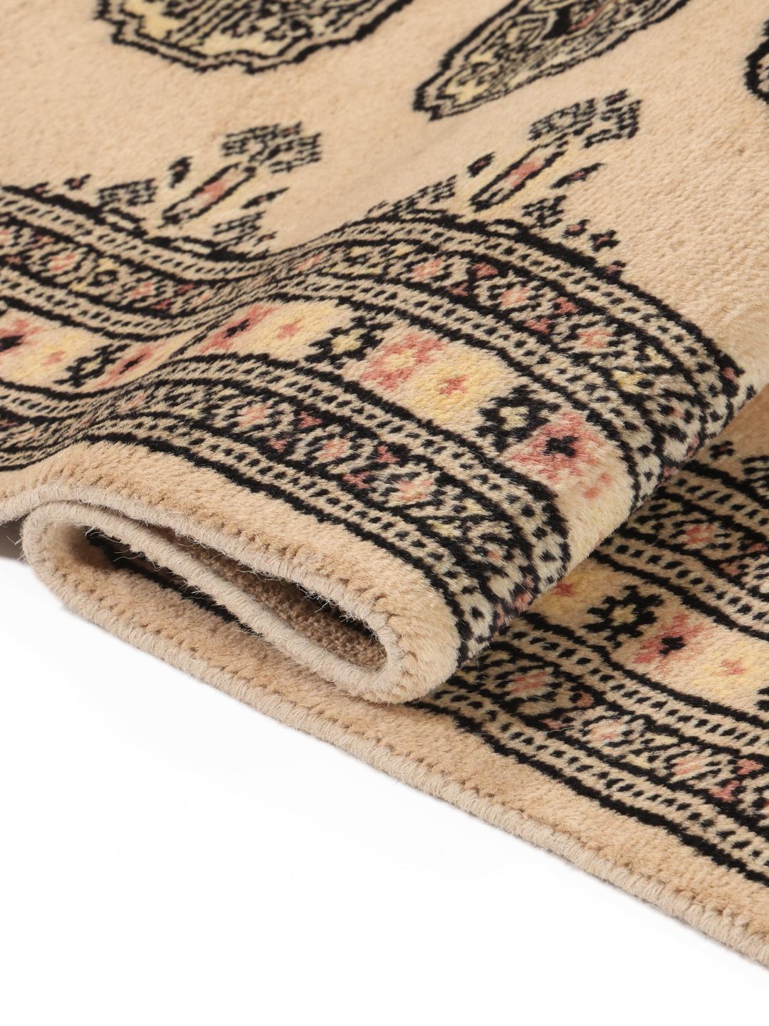 A hand-knotted Pakistan Bokhara runner rug in a soft beige colour with traditional geometric motifs.