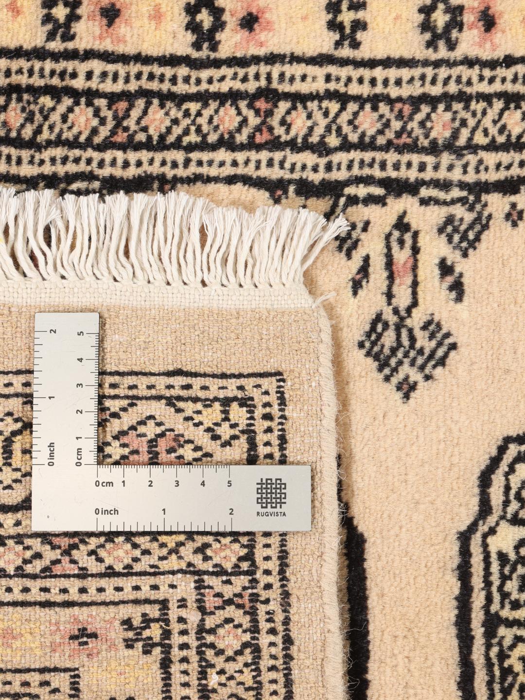 A hand-knotted Pakistan Bokhara runner rug in a soft beige colour with traditional geometric motifs.