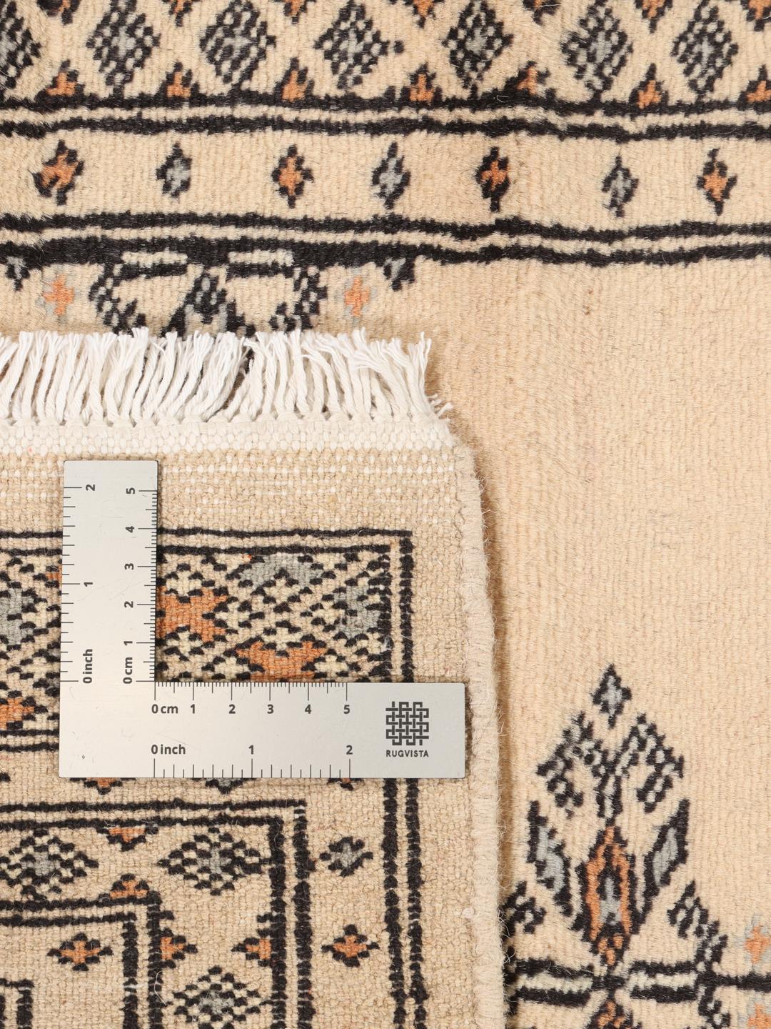 A hand-knotted Pakistani runner rug in beige with a traditional tribal pattern.