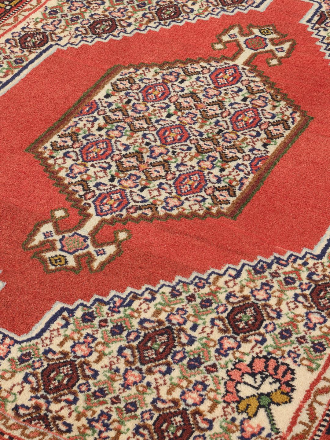 A hand-knotted Senneh rug from the Middle East in vibrant red tones.