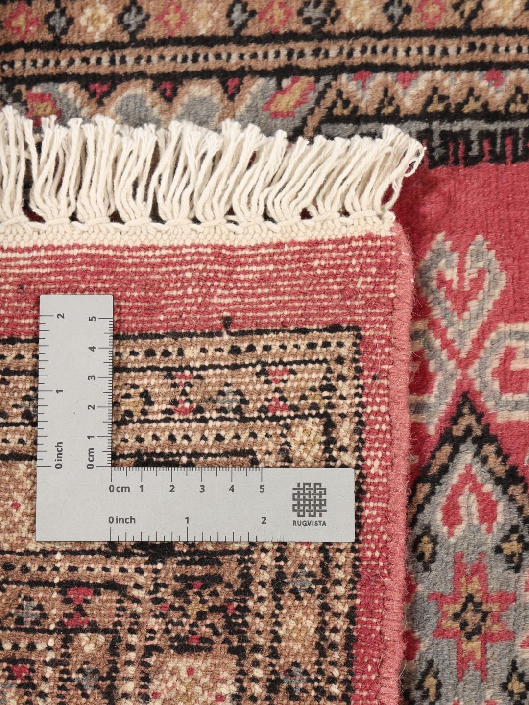 A small, rectangular Pakistan Bokhara 2ply rug in dark-red with geometric medallions.