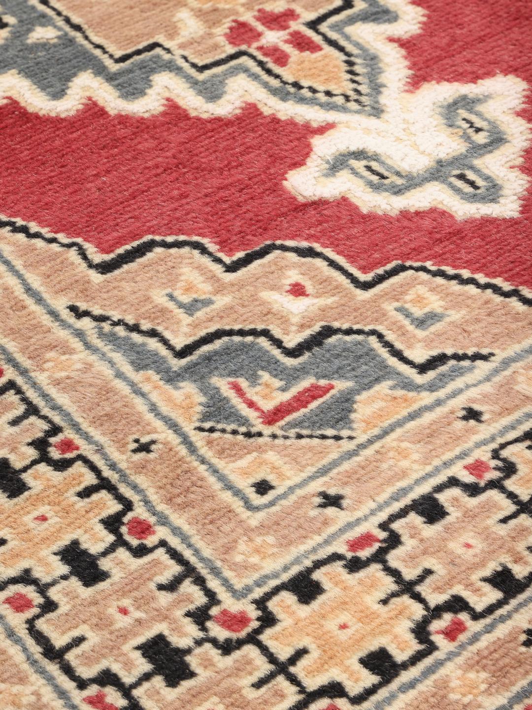 A hand-knotted Pakistan Bokhara wool rug featuring a red and beige geometric design.