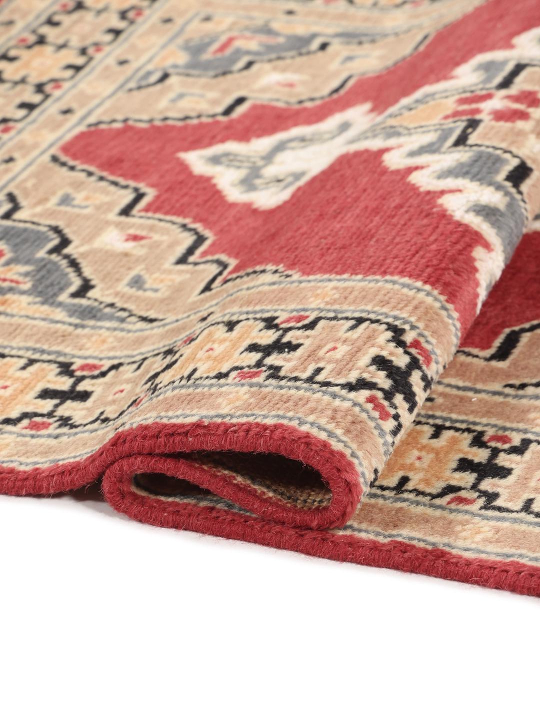 A hand-knotted Pakistan Bokhara wool rug featuring a red and beige geometric design.