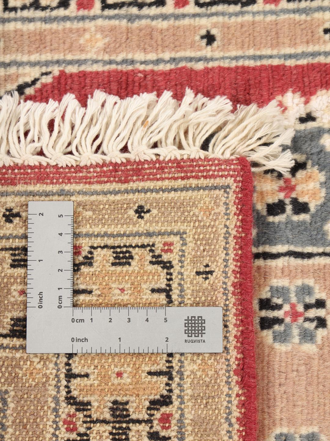 A hand-knotted Pakistan Bokhara wool rug featuring a red and beige geometric design.
