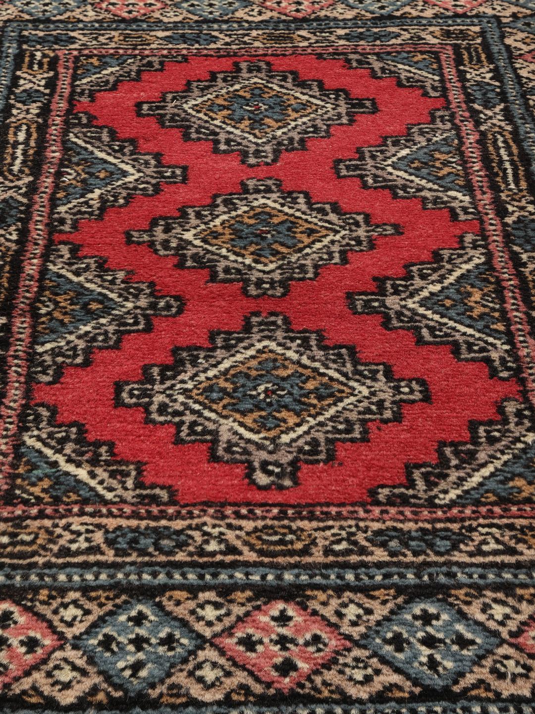 Hand-knotted Pakistan Bokhara rug in red with traditional geometric patterns