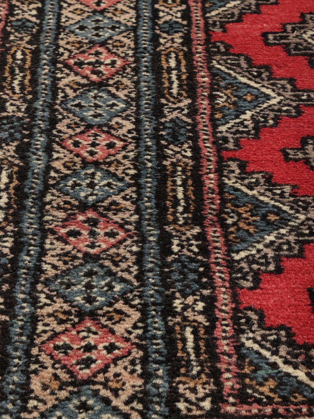 Hand-knotted Pakistan Bokhara rug in red with traditional geometric patterns