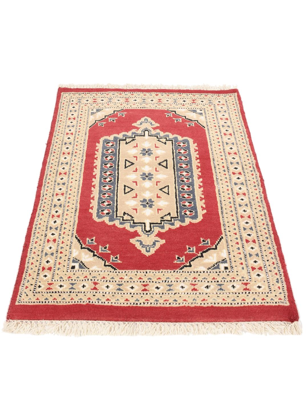 A hand-knotted Pakistan Bokhara rug with a red field and geometric medallion in a home setting.