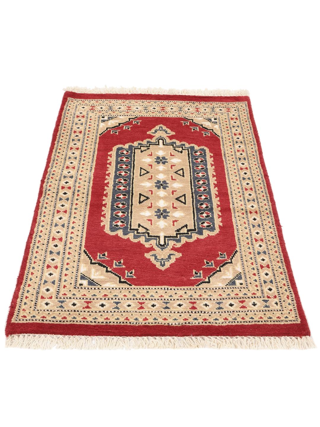 A hand-knotted Pakistan Bokhara rug with a red field and geometric medallion in a home setting.