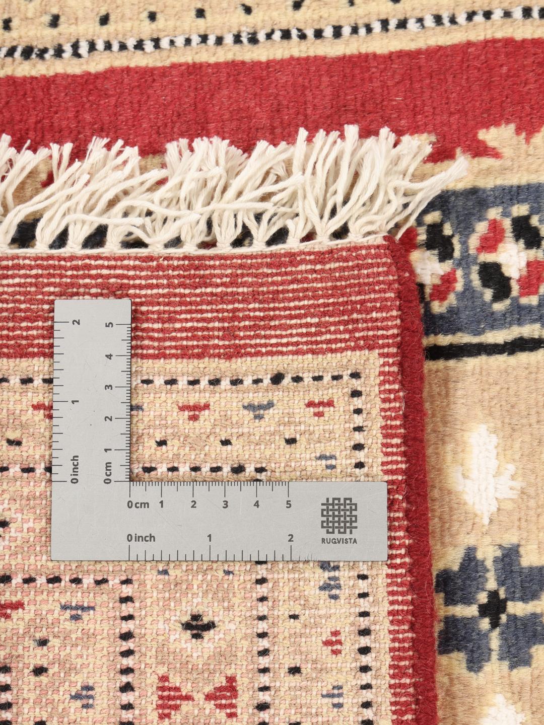 A hand-knotted Pakistan Bokhara rug with a red field and geometric medallion in a home setting.