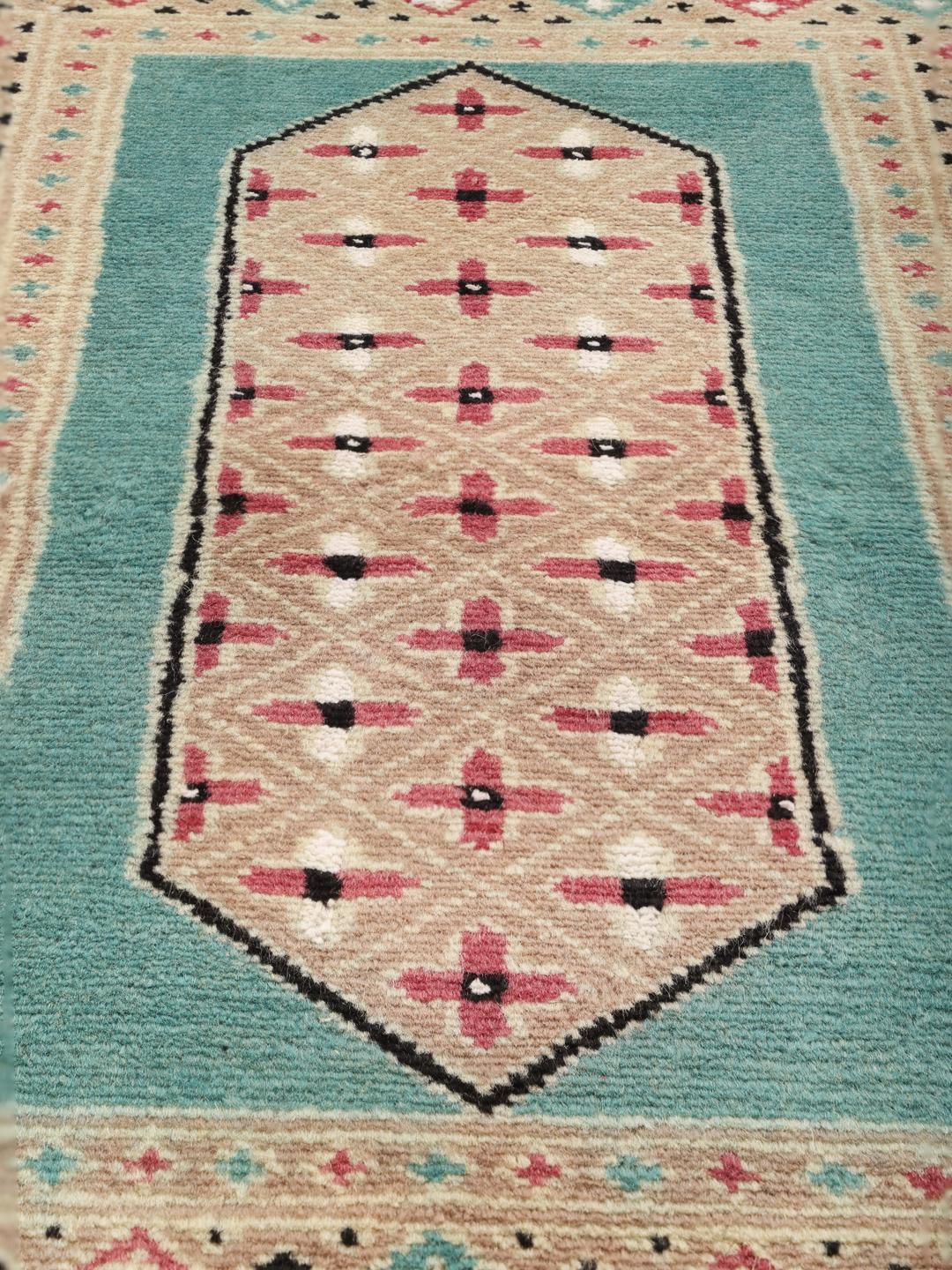 A hand-knotted Pakistan Bokhara 2ply rug with a teal border and geometric medallion pattern