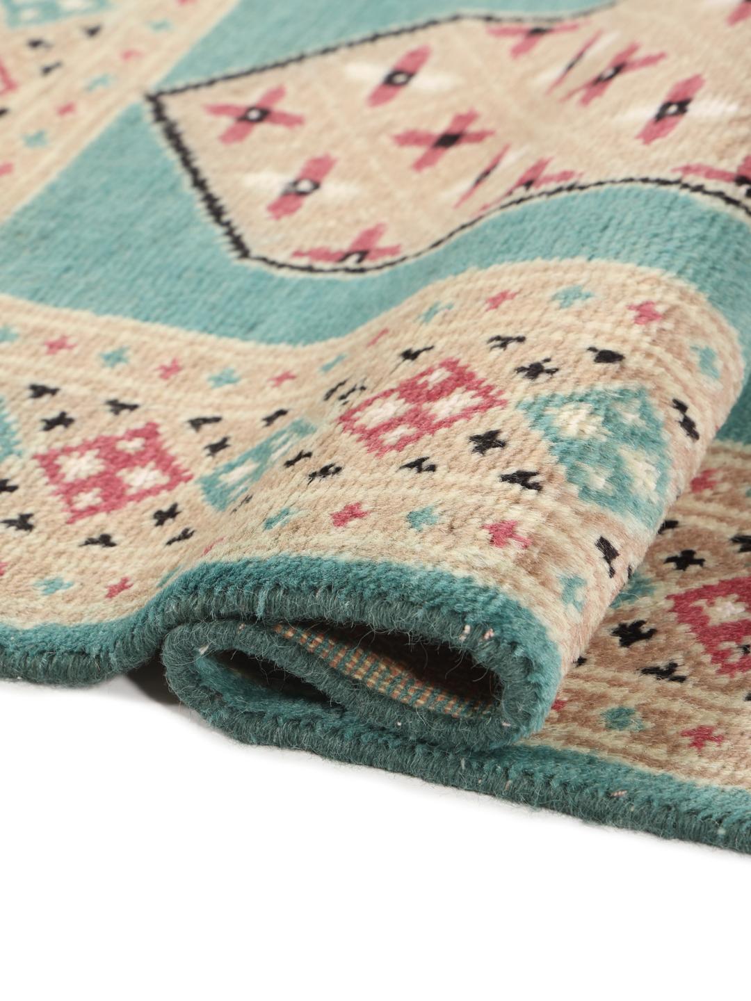 A hand-knotted Pakistan Bokhara 2ply rug with a teal border and geometric medallion pattern