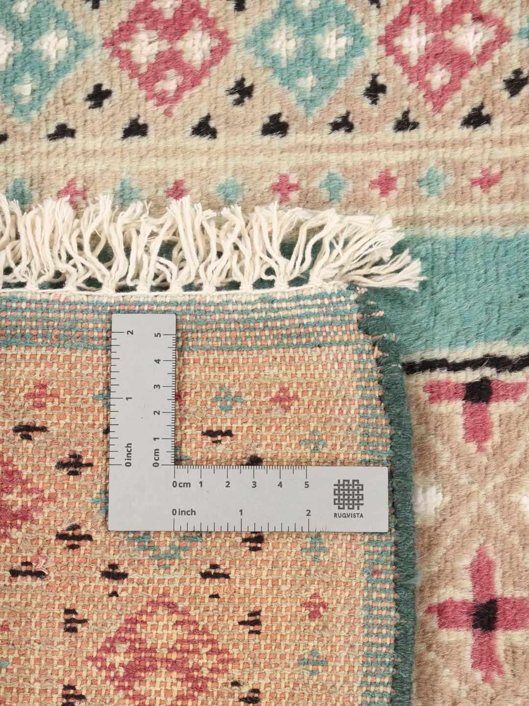 A hand-knotted Pakistan Bokhara 2ply rug with a teal border and geometric medallion pattern