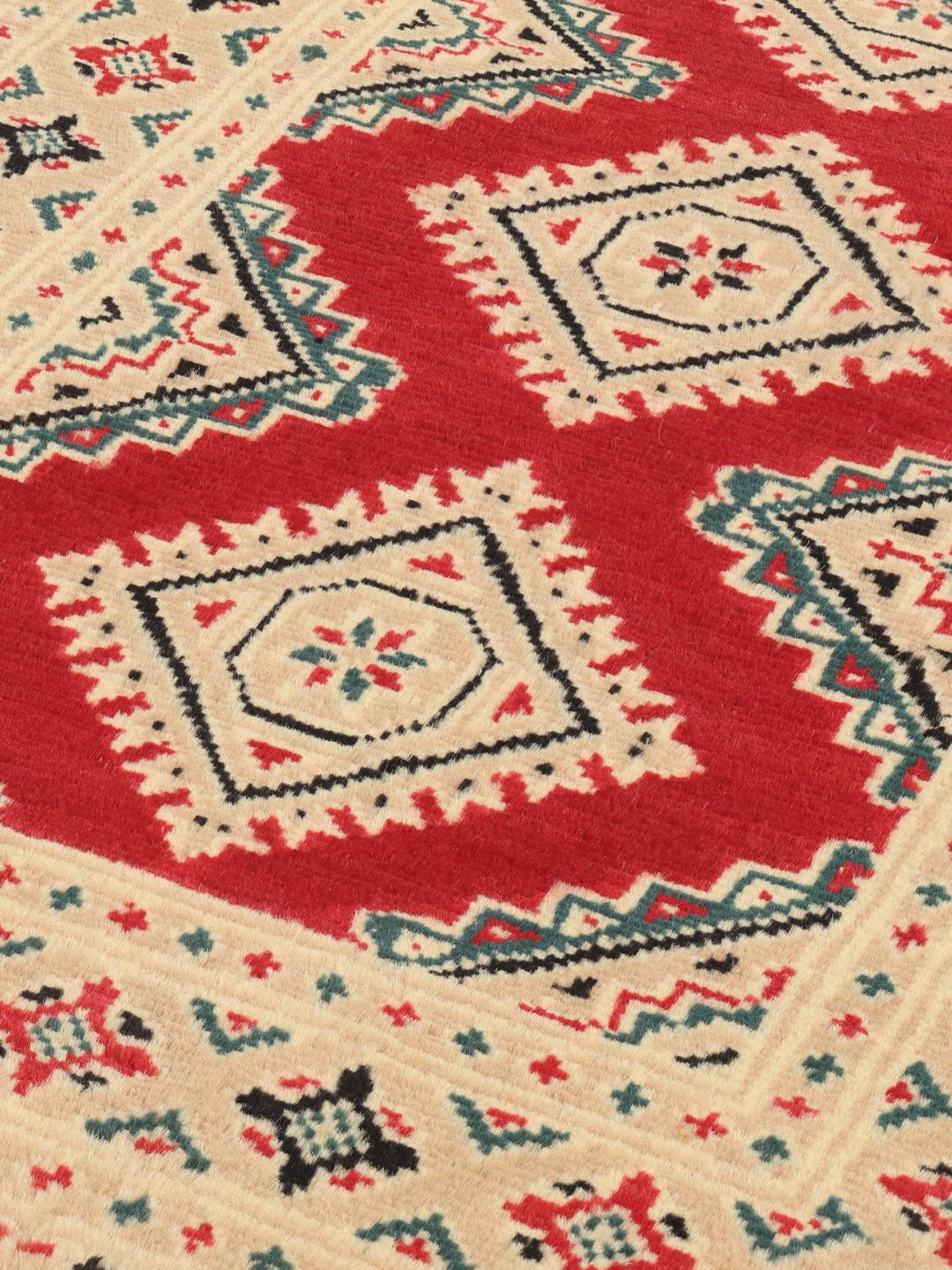 A hand-knotted Pakistan Bokhara rug in red and beige with geometric medallions
