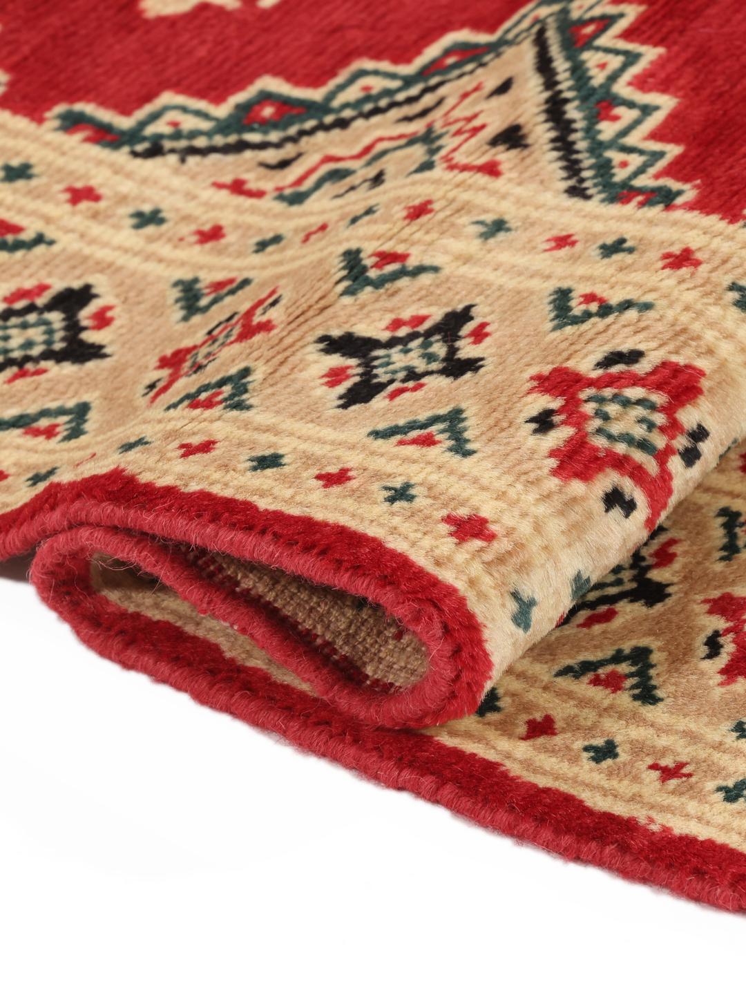 A hand-knotted Pakistan Bokhara rug in red and beige with geometric medallions