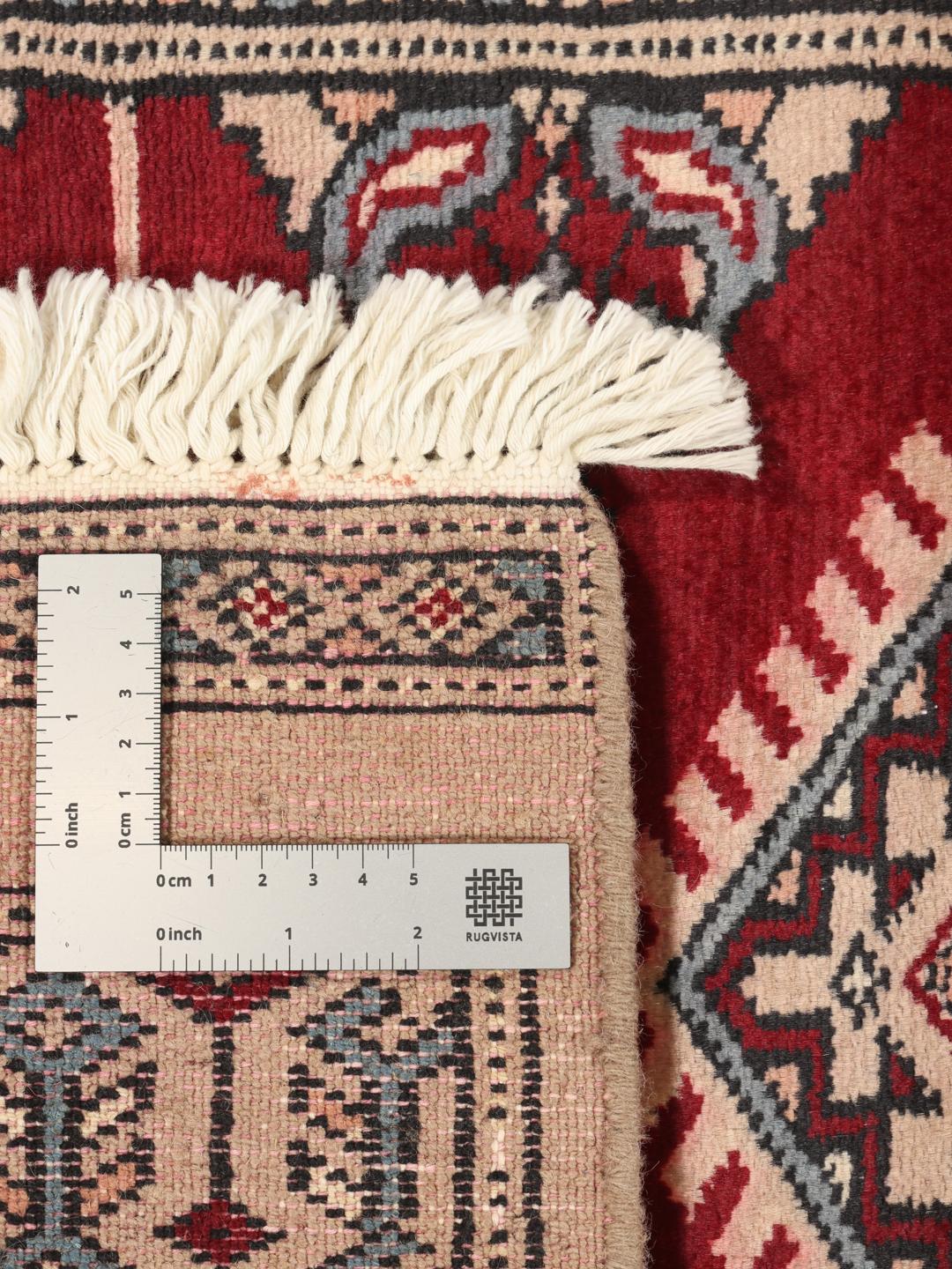 A hand-knotted Pakistan Bokhara rug in red and beige tones with traditional geometric motifs.
