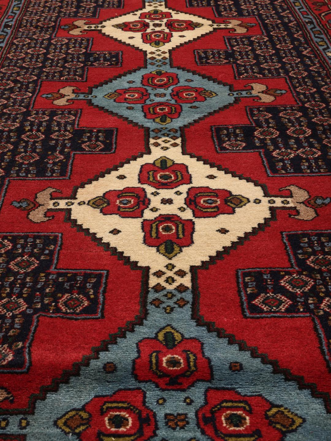 Hand-knotted Senneh runner with a red field and decorative medallion pattern