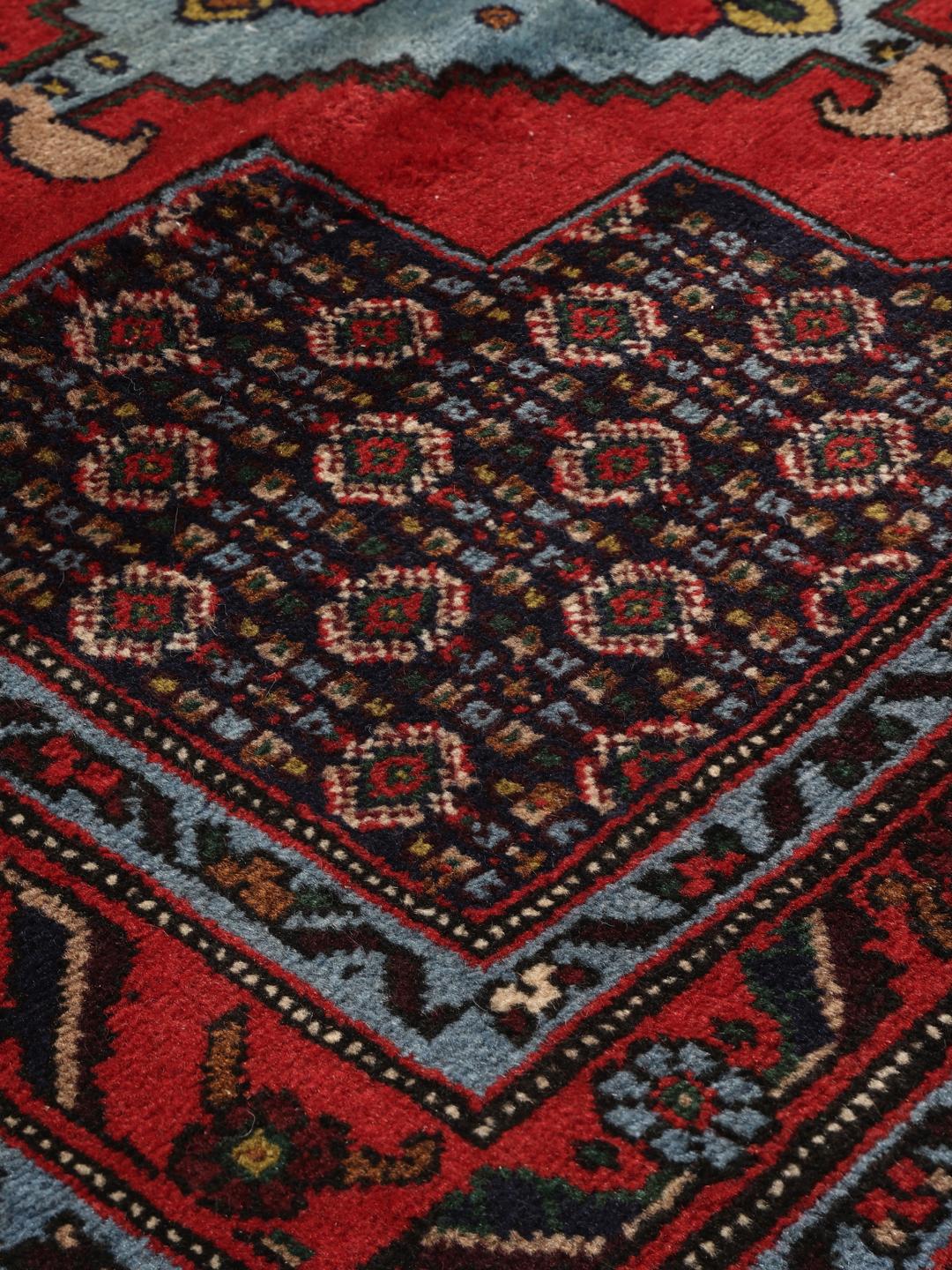 Hand-knotted Senneh runner with a red field and decorative medallion pattern