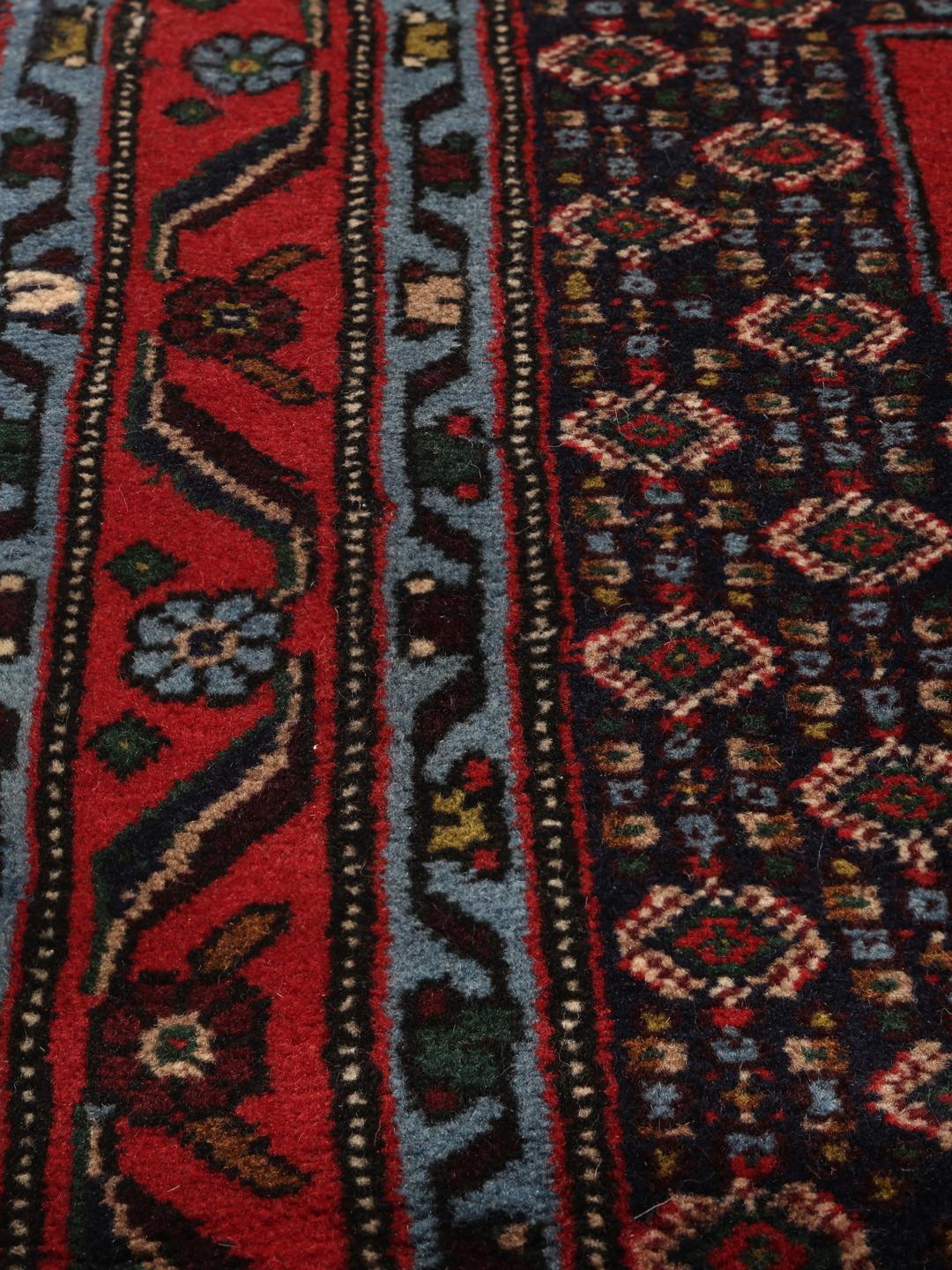 Hand-knotted Senneh runner with a red field and decorative medallion pattern