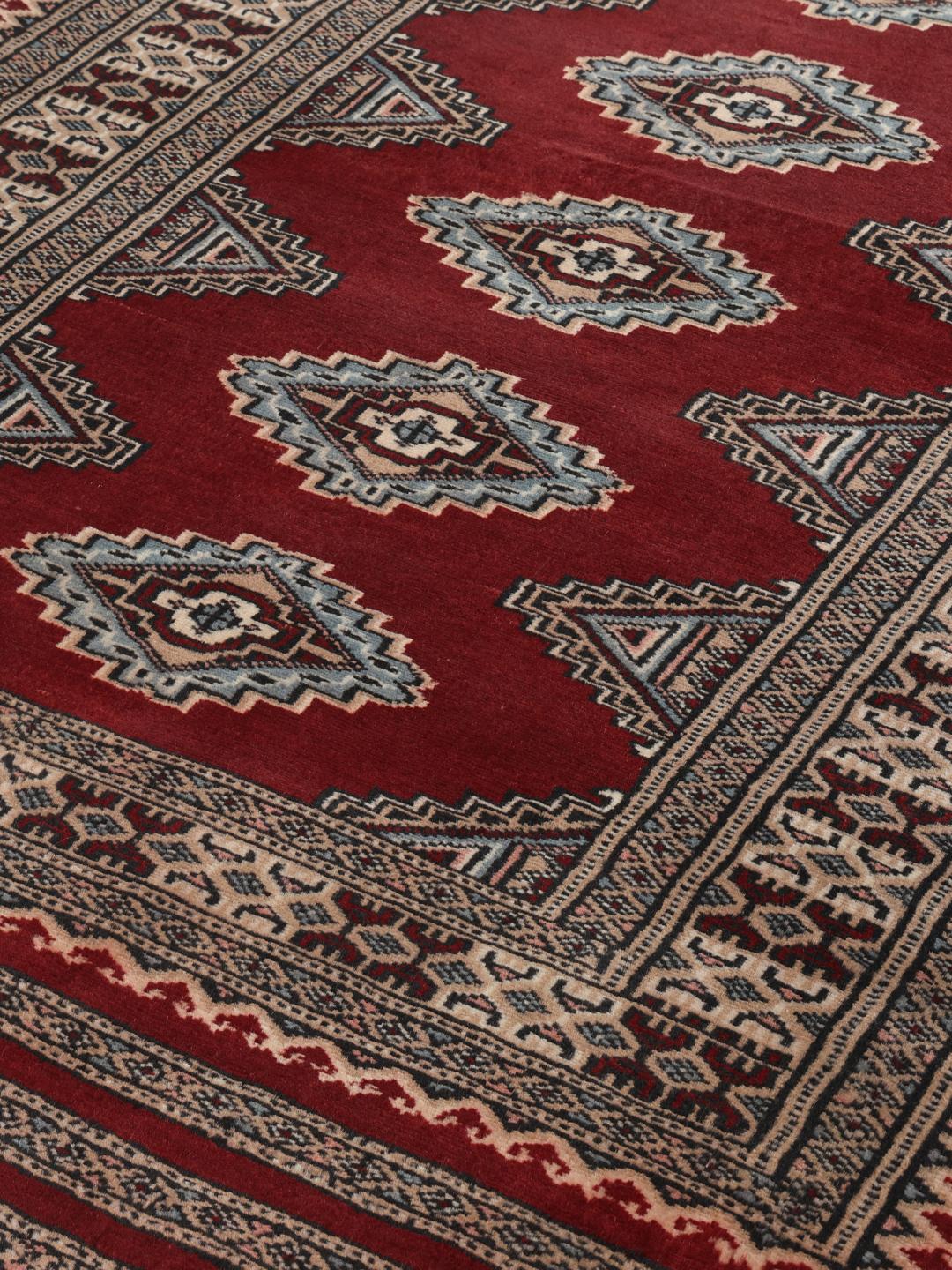 A hand-knotted red Pakistan Bokhara 3ply rug with geometric motifs.