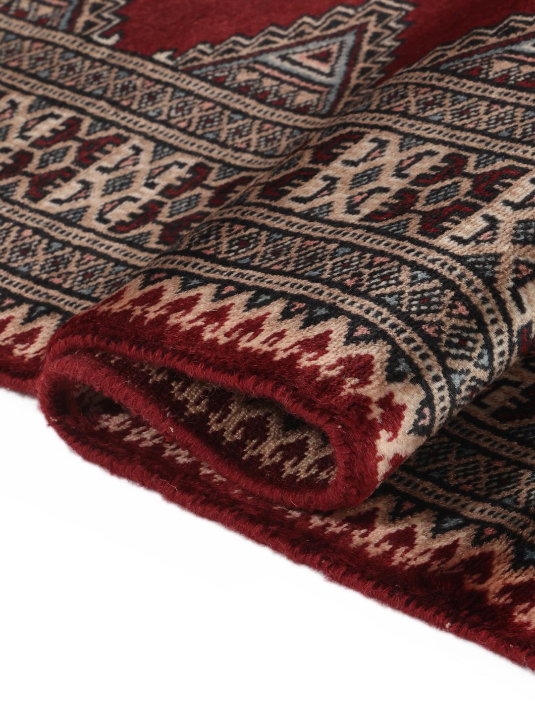 A hand-knotted red Pakistan Bokhara 3ply rug with geometric motifs.