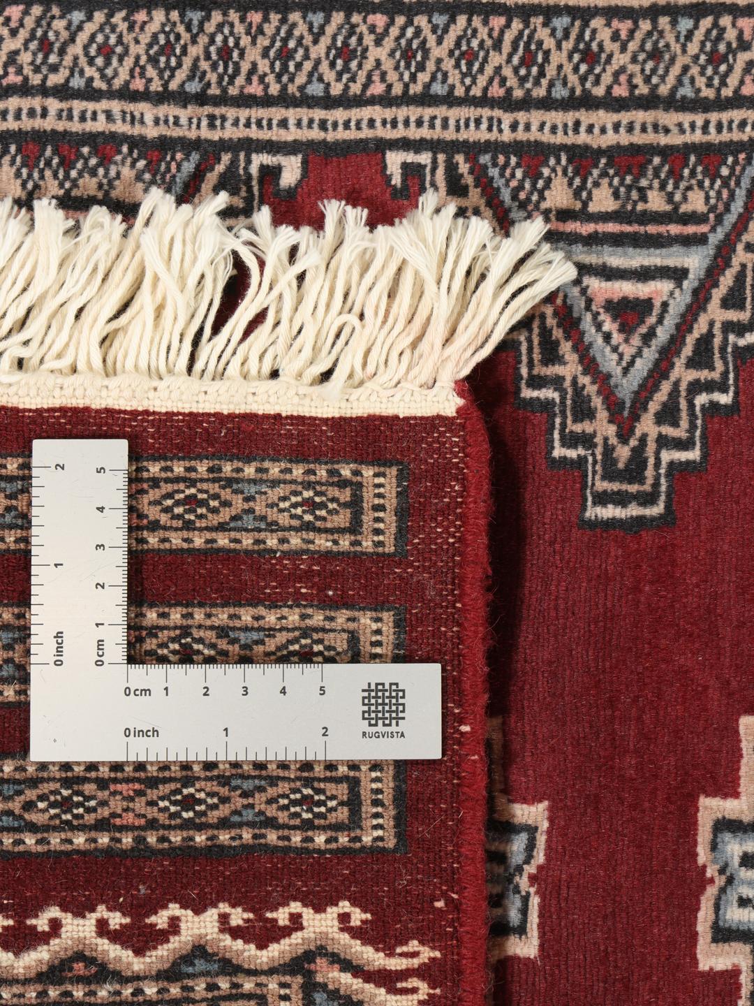 A hand-knotted red Pakistan Bokhara 3ply rug with geometric motifs.