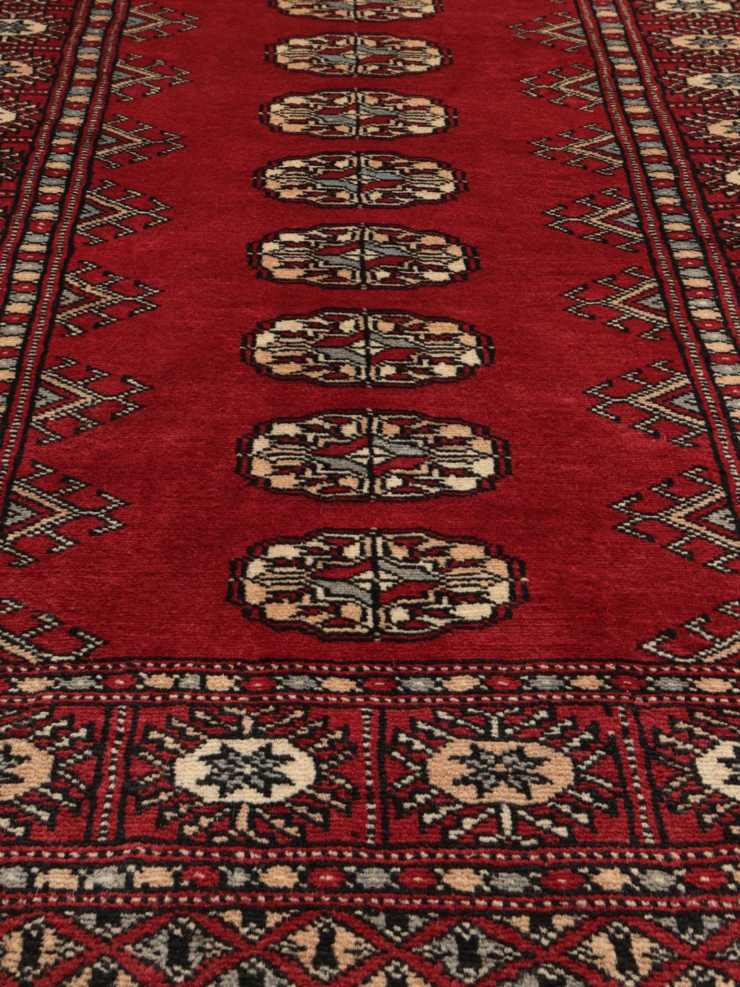 A hand-knotted Pakistan Bokhara rug with a dark-red field and classic repeating motifs.