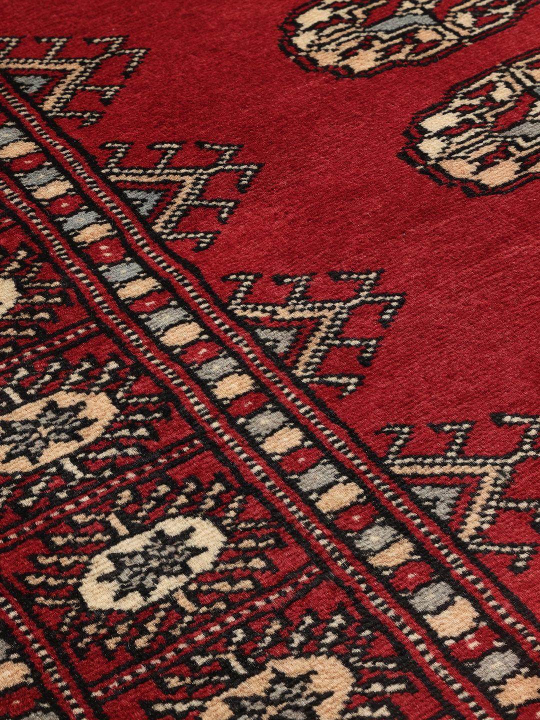 A hand-knotted Pakistan Bokhara rug with a dark-red field and classic repeating motifs.