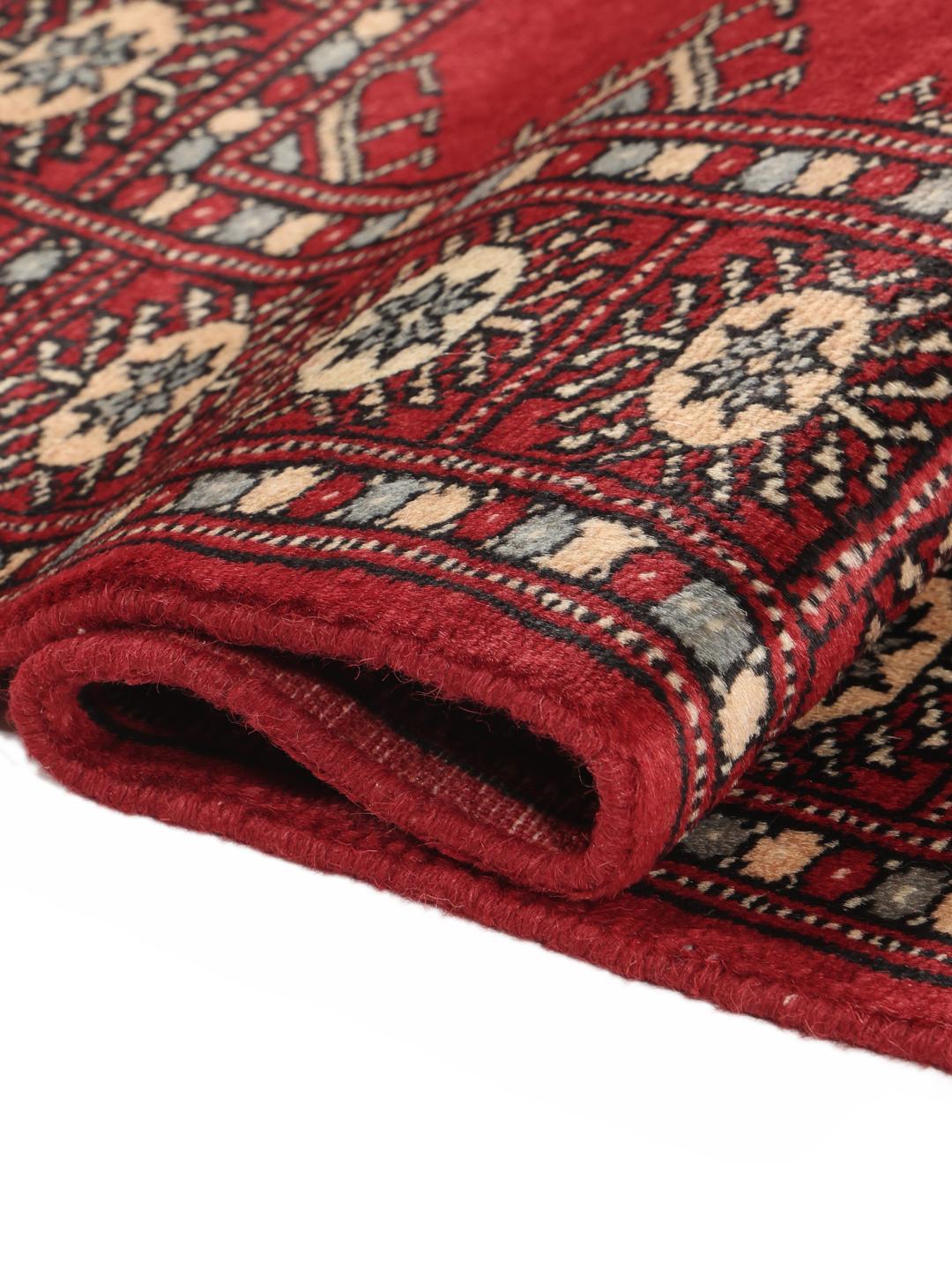 A hand-knotted Pakistan Bokhara rug with a dark-red field and classic repeating motifs.