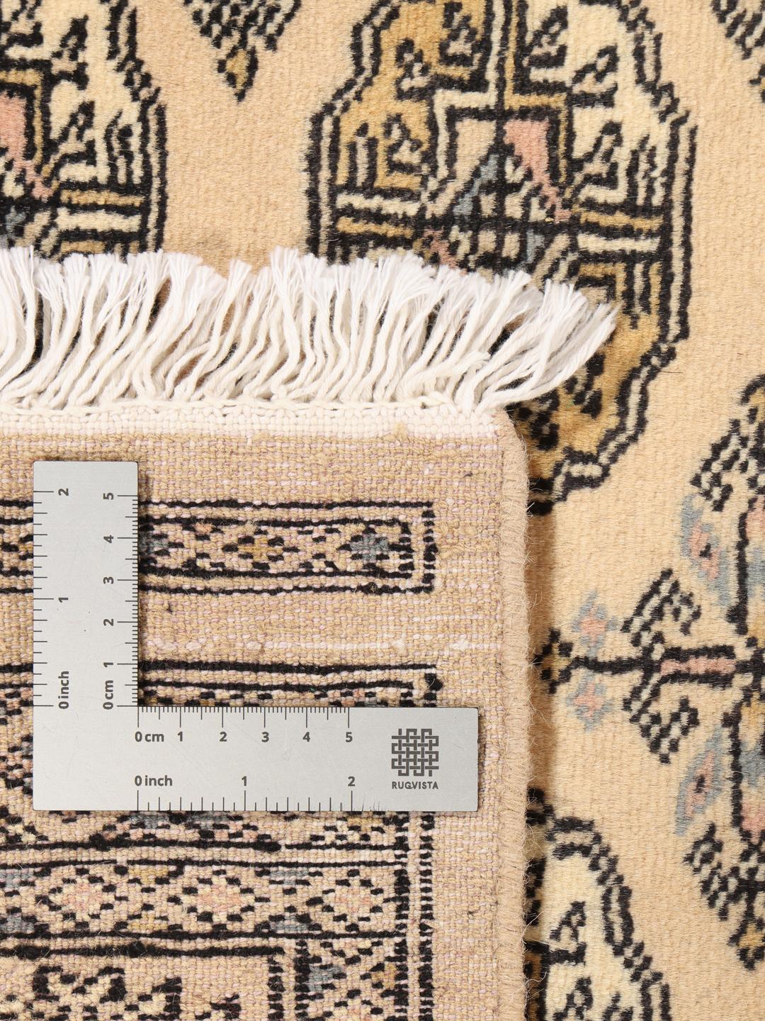 A hand-knotted Pakistan Bokhara rug with a beige field and traditional geometric motifs.