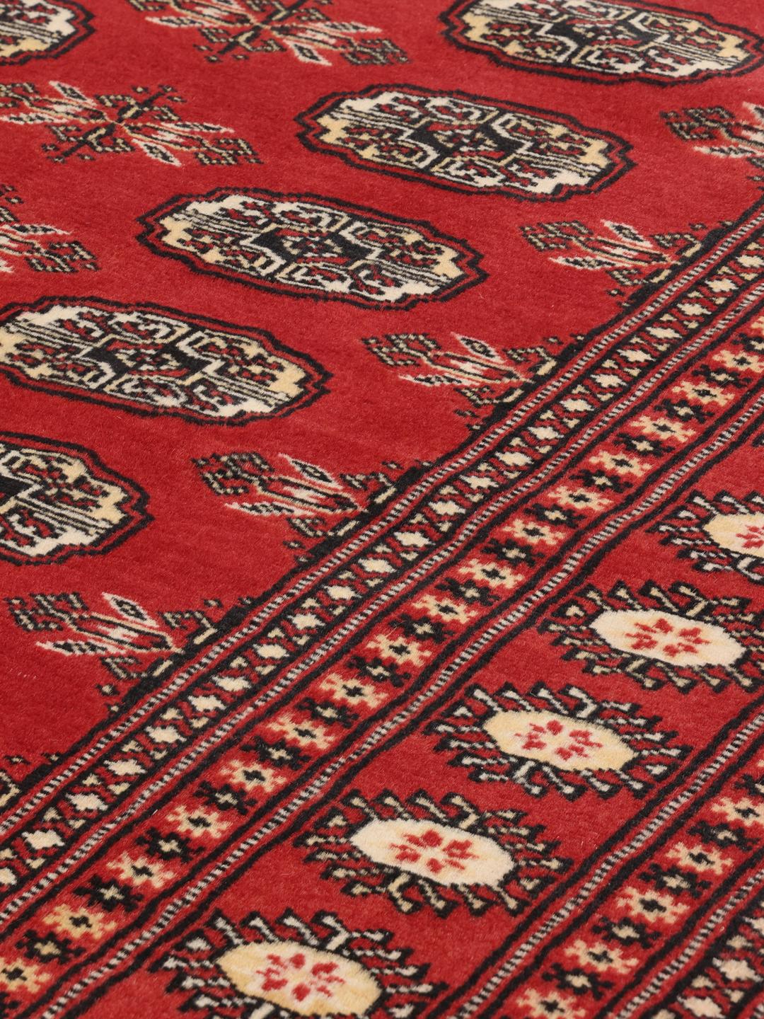 Hand-knotted Pakistan Bokhara 2ply rug with a deep red field and traditional motifs