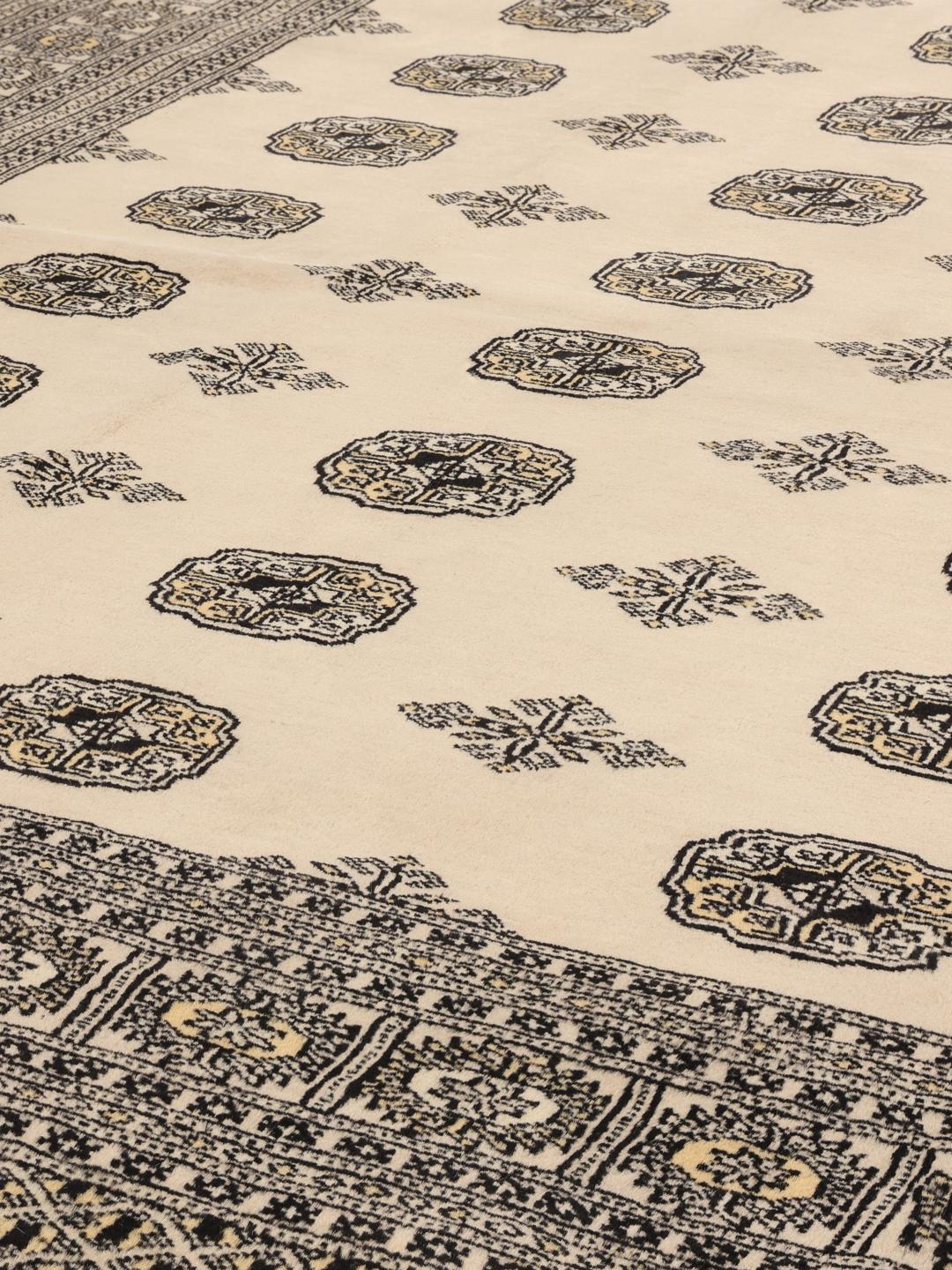Een handgeknoopt Pakistan Bokhara tapijt met een beige veld en traditionele motieven.