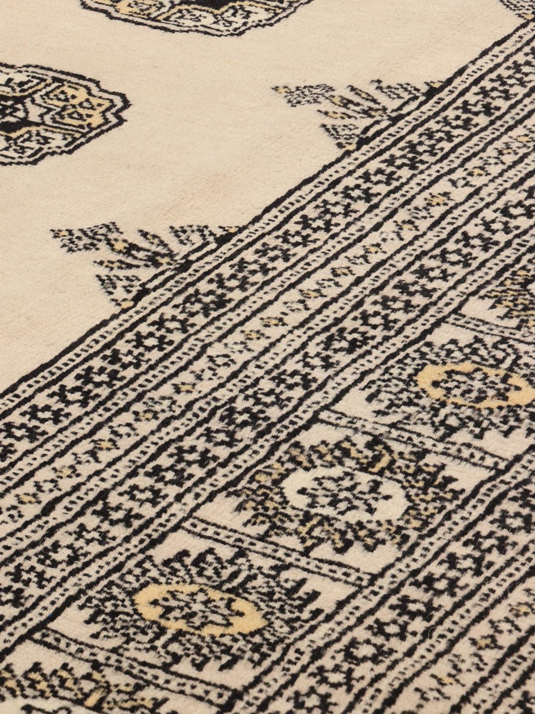 Een handgeknoopt Pakistan Bokhara tapijt met een beige veld en traditionele motieven.