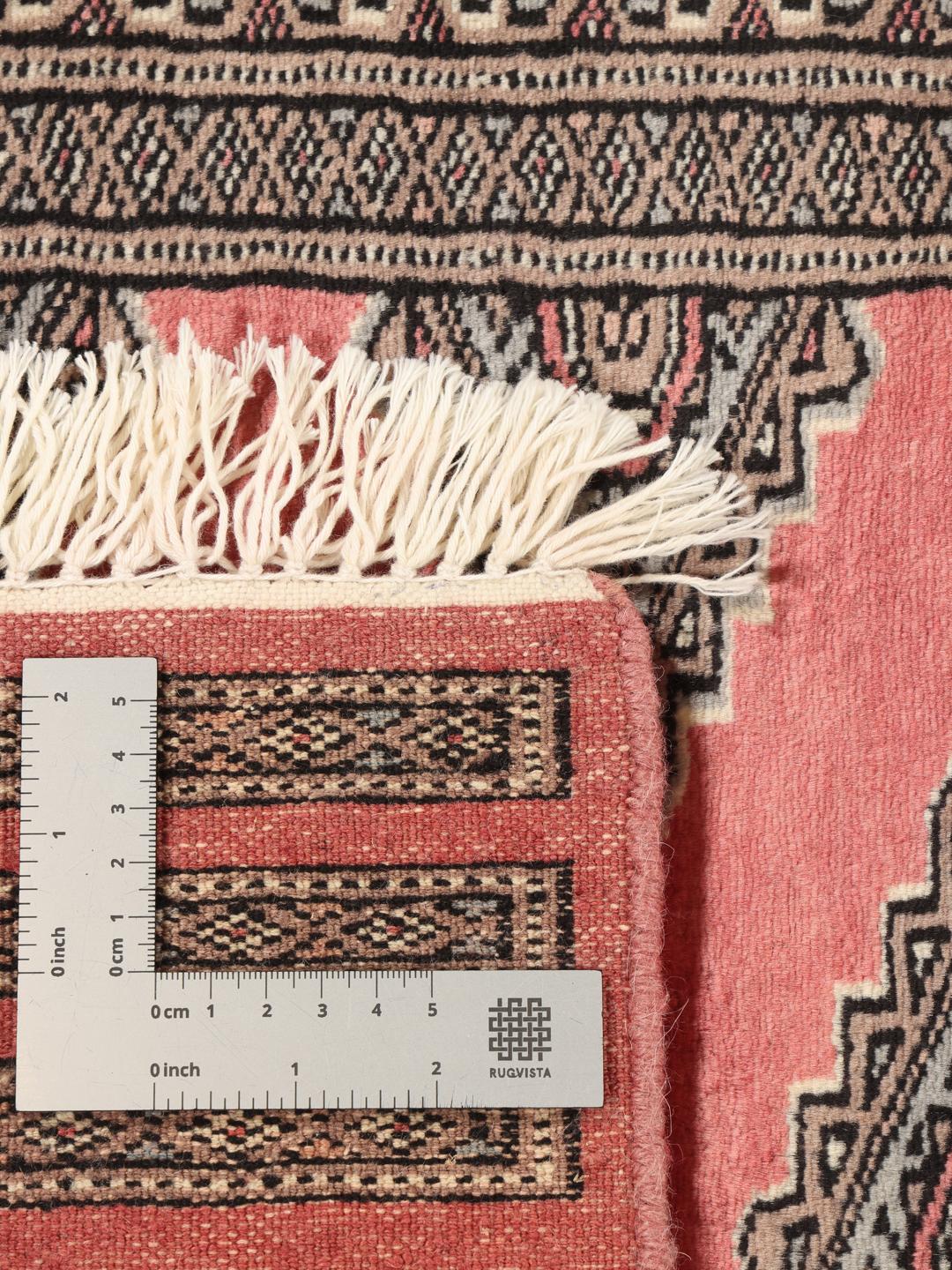 A hand-knotted red Pakistan Bokhara rug with traditional geometric motifs.