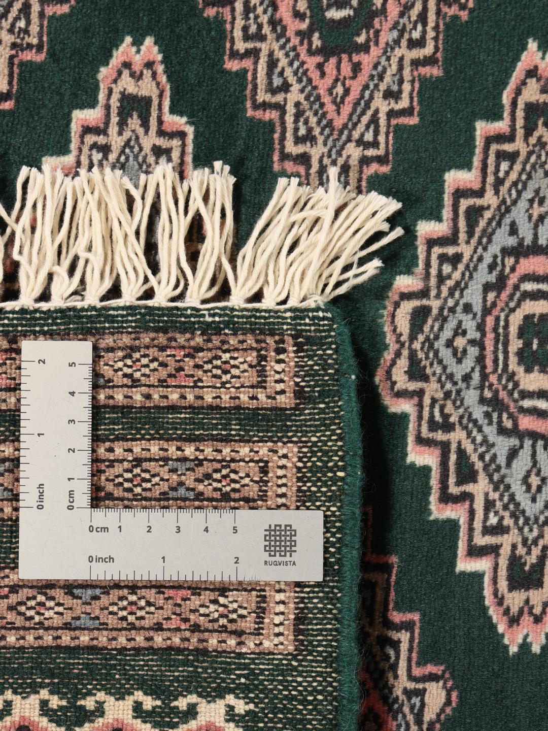A hand-knotted Pakistan Bokhara rug with a dark green field and geometric patterns.