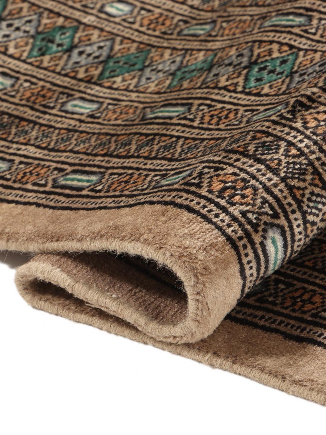A hand-knotted Pakistan Bokhara rug with a vibrant green field and intricate diamond motifs.