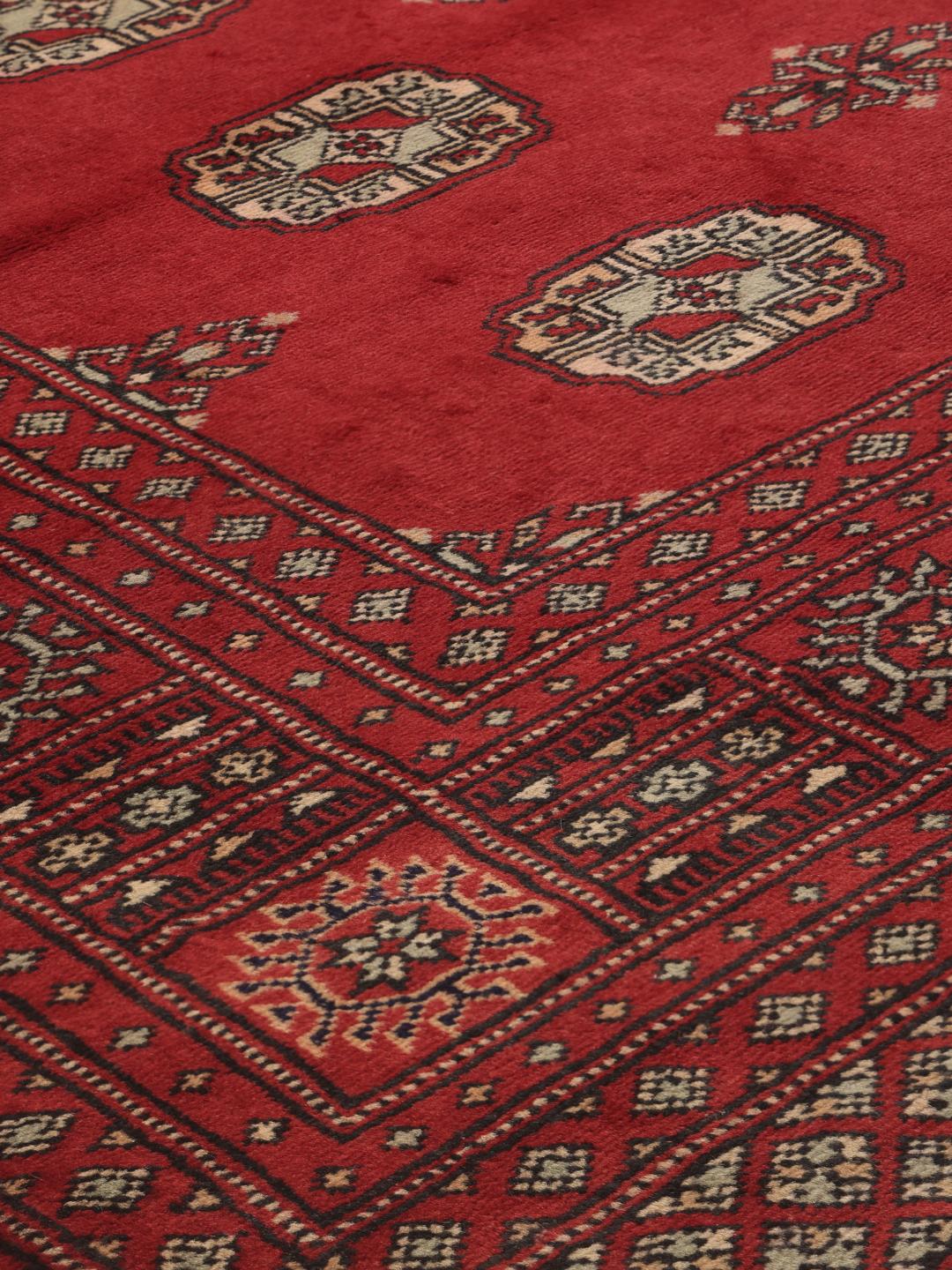 A hand-knotted Pakistan Bokhara 2ply rug in deep red with traditional medallion patterns.