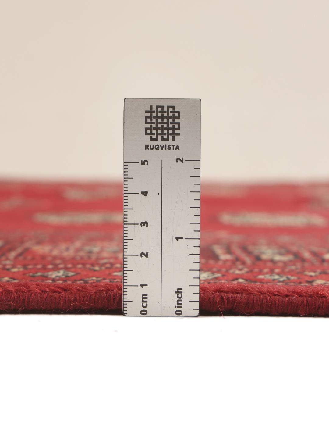 A hand-knotted Pakistan Bokhara 2ply rug in deep red with traditional medallion patterns.