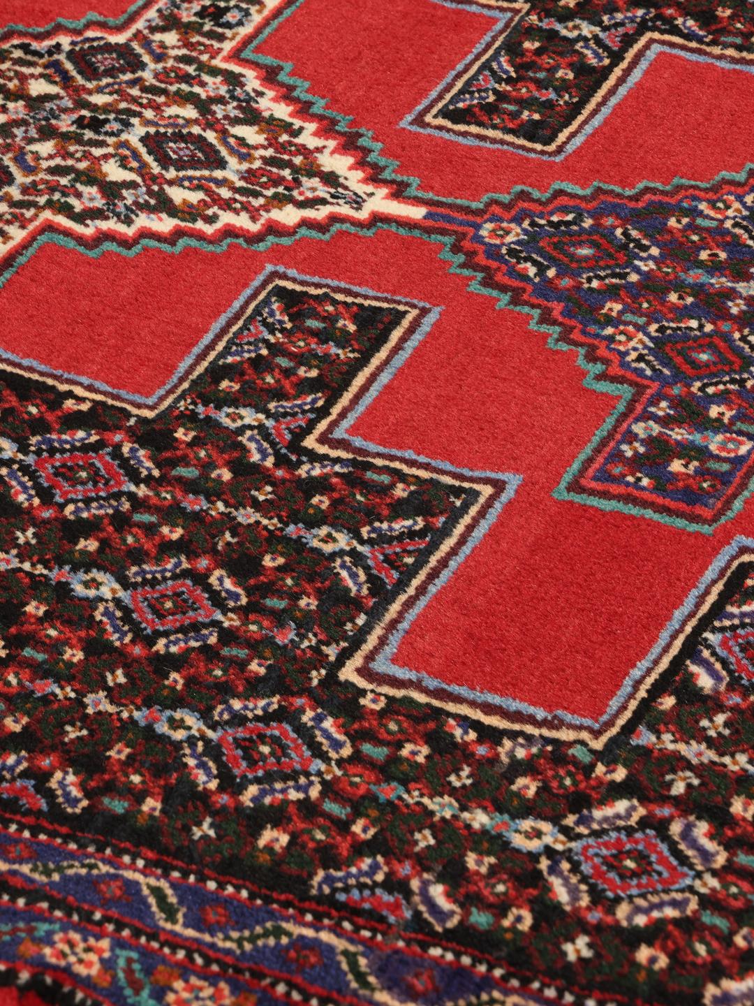 A hand-knotted Senneh runner from the Middle East in dark-red and black tones.