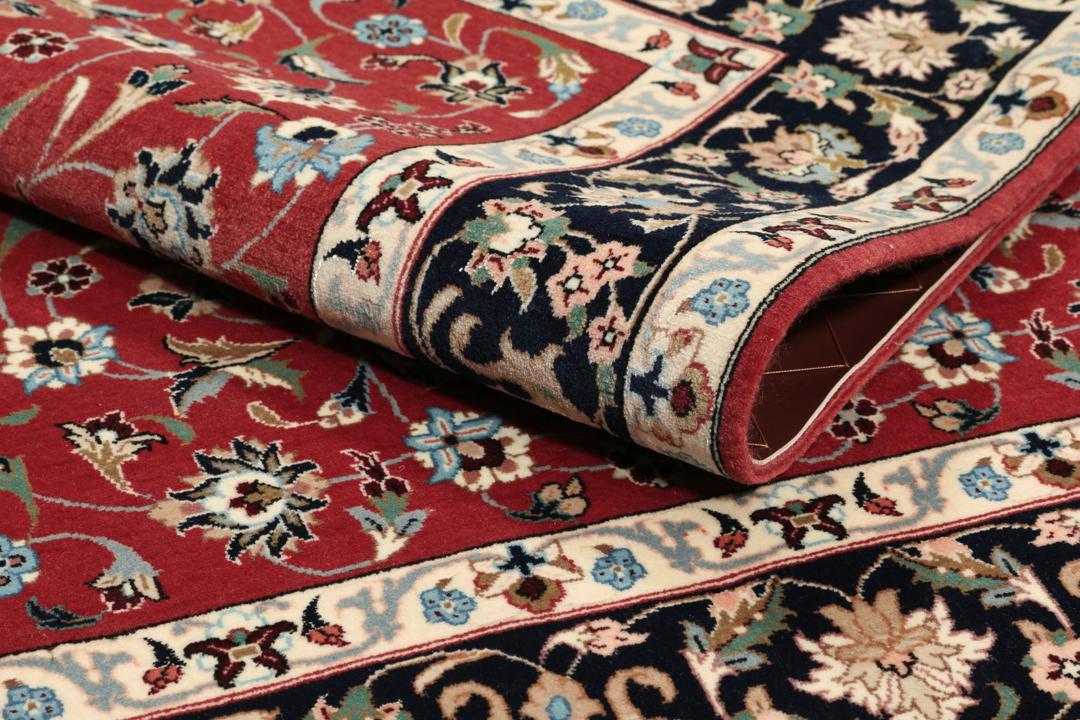 Een met de hand geknoopt Ilam Sherkat Farsh tapijt uit het Midden-Oosten met een rood veld en donkere bloemenranden.