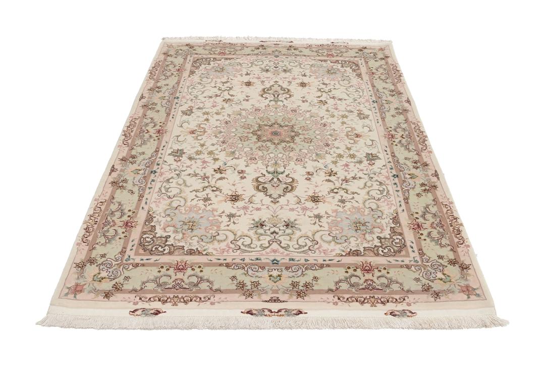 Een handgeknoopt Tabriz-tapijt uit het Midden-Oosten met een bloemenmedaillonpatroon in groen en roze.