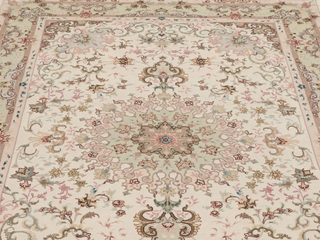 Een handgeknoopt Tabriz-tapijt uit het Midden-Oosten met een bloemenmedaillonpatroon in groen en roze.