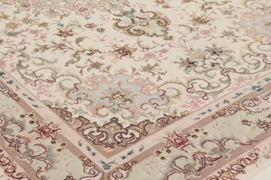 Een handgeknoopt Tabriz-tapijt uit het Midden-Oosten met een bloemenmedaillonpatroon in groen en roze.