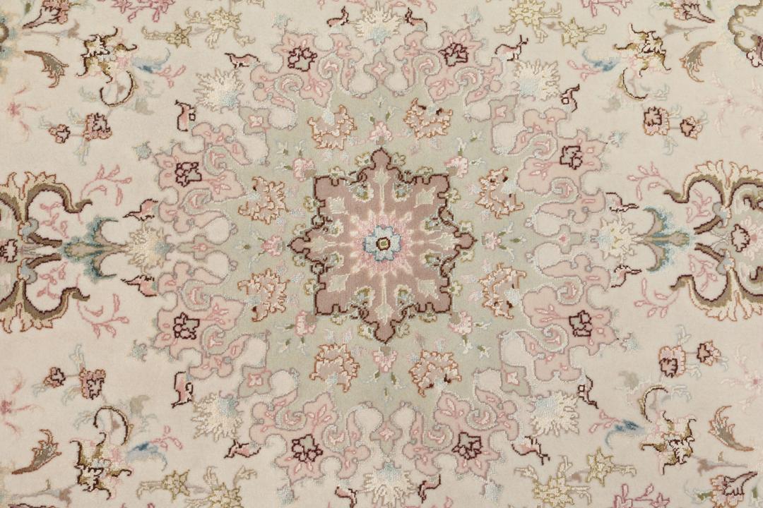 Een handgeknoopt Tabriz-tapijt uit het Midden-Oosten met een bloemenmedaillonpatroon in groen en roze.