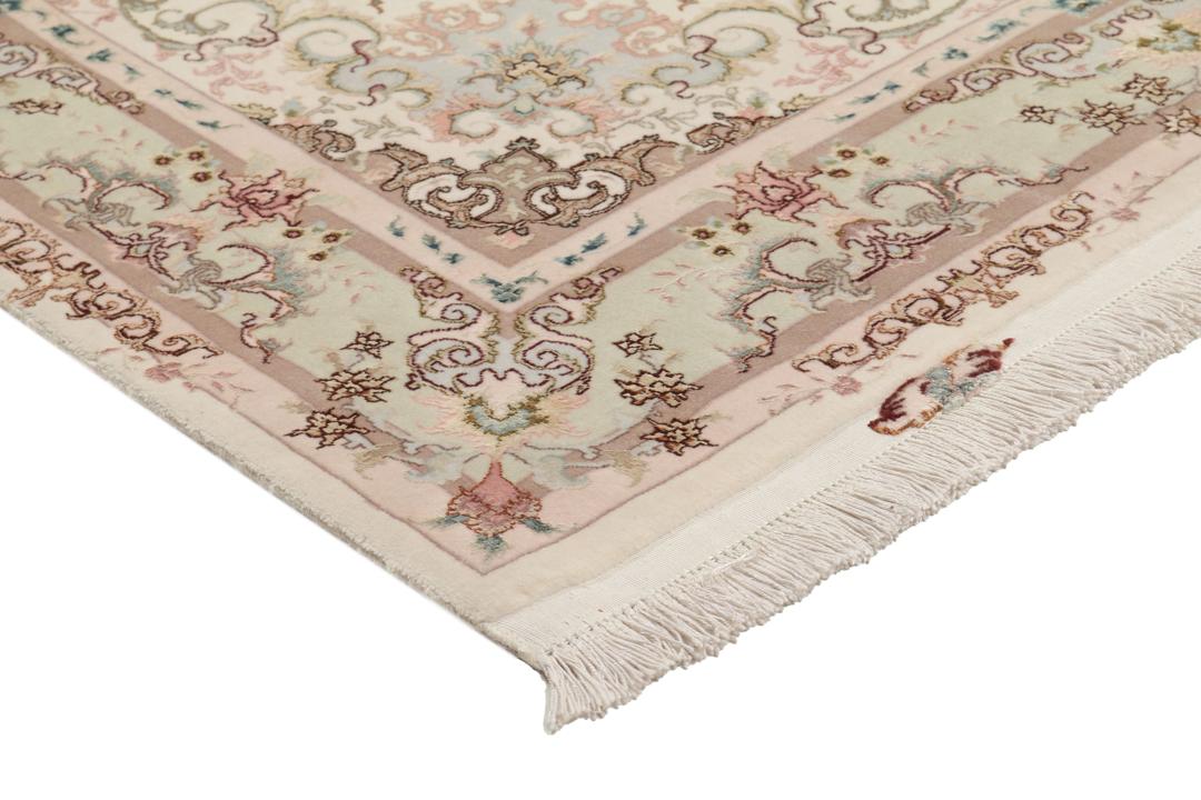 Een handgeknoopt Tabriz-tapijt uit het Midden-Oosten met een bloemenmedaillonpatroon in groen en roze.