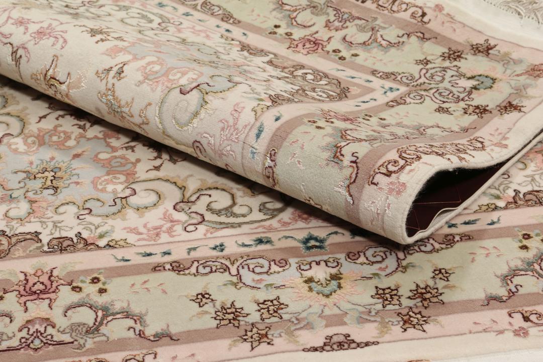 Een handgeknoopt Tabriz-tapijt uit het Midden-Oosten met een bloemenmedaillonpatroon in groen en roze.