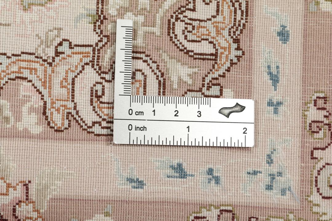 Een handgeknoopt Tabriz-tapijt uit het Midden-Oosten met een bloemenmedaillonpatroon in groen en roze.